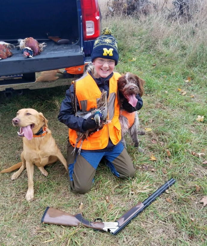 Young hunter with pheasant and dogs